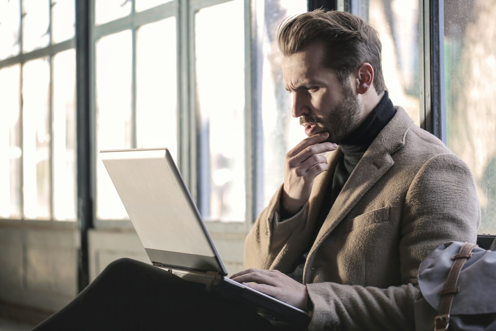 Man thinking with hand on chin at his laptop, representing cognitive debt from AI reliance